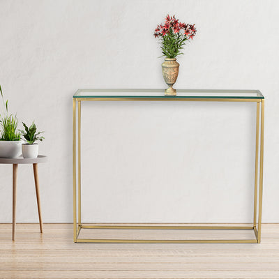 Rectangle console table with glass top supported by metal legs in gold finish