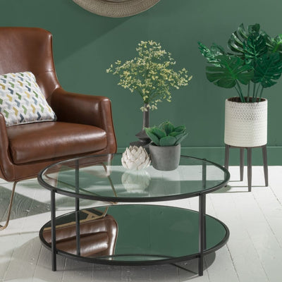 Round shape coffee table with two-tiered shelf top with glass and bottom with mirror, supported by metal legs in black finish