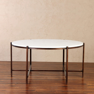 Round coffee table with white marble top supported by metal frame in bronze finish