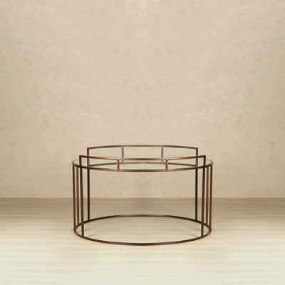 Round coffee table with glass top supported by metal legs in gold finish